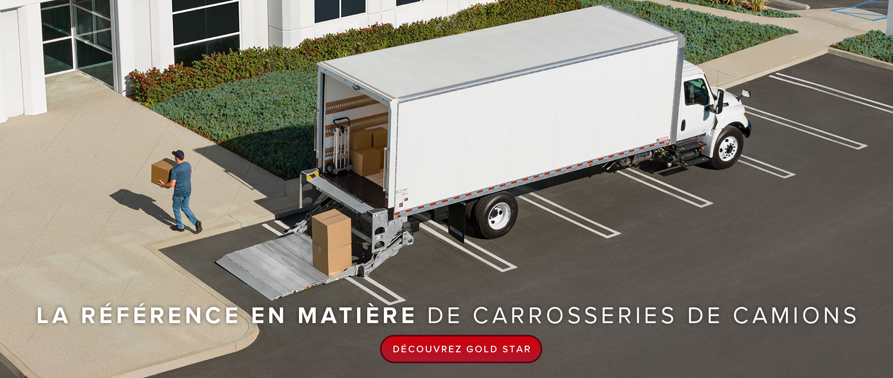 Un grand camion blanc pour fret sec est garé devant un immeuble de bureaux. Un livreur porte une boîte vers la porte d'entrée.